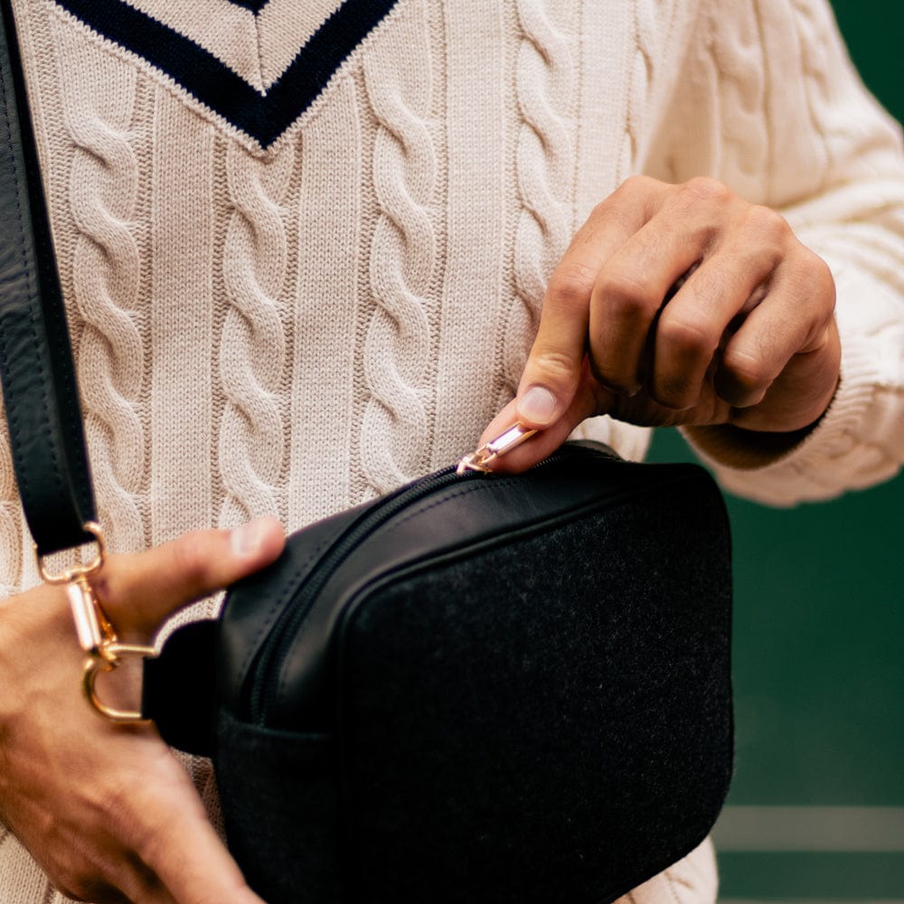 Man opening the zip of the Black Italian Wool Crossbody Bag